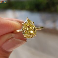 a yellow diamond is being held in someone's hand with the ring on it