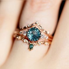 a woman's hand holding a ring with a blue stone and diamond accents on it