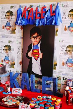 a superman themed birthday party with cupcakes, cake and photo on the table