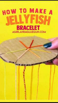 a person holding up a piece of cardboard with yarn on it and the text how to make a jellyfish bracelet