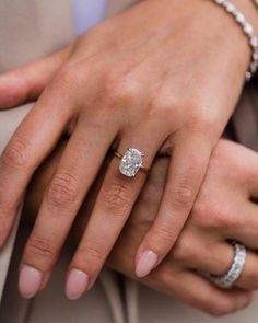 a close up of two people's hands wearing wedding rings and diamond bracelets