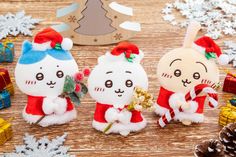 three small stuffed animals sitting on top of a wooden table next to christmas decorations and pine cones