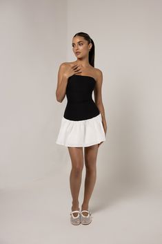 Introducing the Black Strapless Colorblock Flare Mini Dress, a chic and versatile piece that combines modern style with a playful silhouette. Featuring a sleek black strapless bodice that highlights the neckline and shoulders, the dress contrasts with a flared white skirt for a flattering colorblock design. The fitted top hugs the body, while the flared skirt adds movement and dimension, making it perfect for both casual and semi-formal occasions. Ideal for summer outings or evening events, this dress effortlessly balances elegance and fun. Chic Strapless Stretch Mini Dress, Chic Off-shoulder Tube Top For Cocktail, Chic Off-shoulder Cocktail Tube Top, Chic Stretch Strapless Dress, Chic Bandeau Mini Dress For Night Out, Summer Black Strapless Mini Dress, Black Strapless Off-shoulder Stretch Dress, Elegant Black Tube Top With Straight Neckline, Black Tube Top For Cocktail