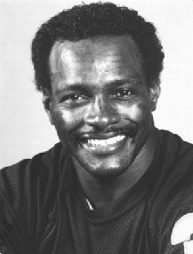 a black and white photo of a football player with his arms crossed, smiling at the camera