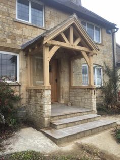 a stone house with a wooden front door and steps leading up to the entryway