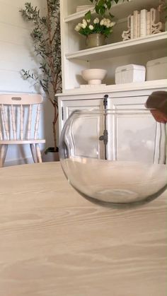 a glass bowl sitting on top of a wooden table next to a white book shelf