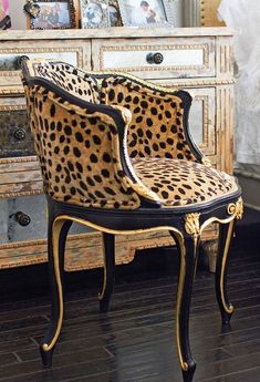 a leopard print chair sitting on top of a hard wood floor next to a dresser