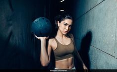 a woman is holding a ball in her right hand and posing for the camera,