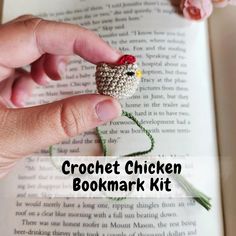 the crochet chicken bookmark kit is being held over an open book