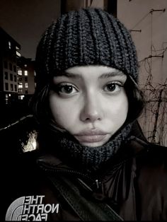 a woman wearing a hat and scarf in front of a building with the north face logo on it