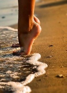 a person walking on the beach with their feet in the water