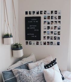 a bed with lots of pillows and pictures on the wall above it, along with hanging planters