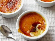 two bowls filled with soup sitting on top of a white table cloth next to silver spoons