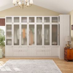 an empty room with white cabinets and wood flooring is shown in front of a chandelier