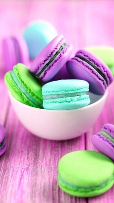 colorful macaroons in a white bowl on a pink table