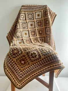 a crocheted blanket sitting on top of a wooden chair