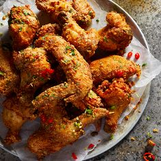 fried chicken wings on a plate with chili peppers and seasoning sprinkles