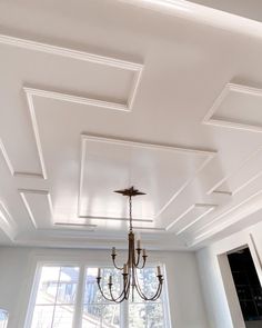 a chandelier hanging from the ceiling in a room with white walls and ceilings