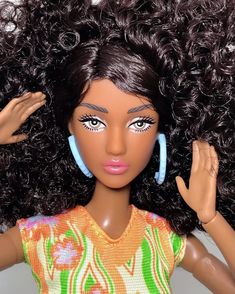 a close up of a doll with curly hair and blue hoop earrings on it's head