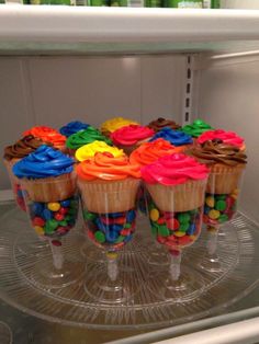 cupcakes with colorful icing on them sitting on a glass plate in front of a microwave