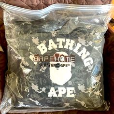 a bag that is sitting on top of a bed with the words bathing ape printed on it