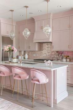 a kitchen with pink chairs and marble counter tops in front of a large center island