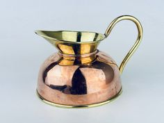 a metal pitcher with a gold handle on a white background