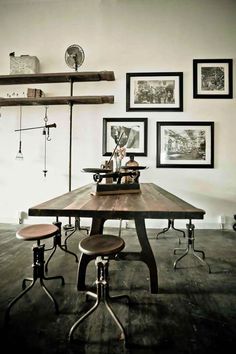 a dining room table with stools and pictures on the wall above it in black and white