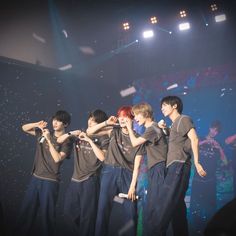 a group of young men standing next to each other on top of a stage with confetti flying in the air