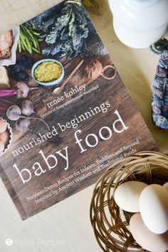 a book about baby food sitting on top of a table next to an egg in a nest