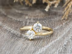 two diamond rings sitting on top of a piece of wood next to some dried flowers