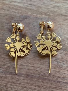 Gorgeous clip on earrings. Dangling gold  coloured dandelion charms on hinged screwback closures. Adjustable.  Earrings are not intended to be worn while sleeping bathing or swimming. Not recommended for children under three. See more: https://www.etsy.com/ca/shop/CleverLittleEars CANADIAN PRICES INCLUDE GST/HST WHERE APPLICABLE. ETSY WILL CALCULATE ANY PST OWING AT CHECKOUT. While the cost of shipping makes returns or exchanges impractical, please do contact me with any concerns about your order and we will work together to address them.  By law, European buyers have 14 days from receipt to request a return. Return shipping costs will not be covered by CleverLittleEars. Earrings Dangling, Clip On, Clip On Earrings, Dandelion, Gold Color, Jewelry Earrings, Charms, Swimming, Etsy Uk