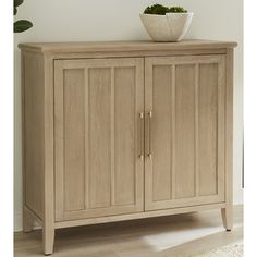 a wooden cabinet sitting on top of a hard wood floor next to a potted plant