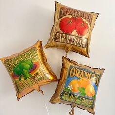 three foil balloons with oranges and broccoli on them are hanging from the wall