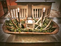 a tray with candles and deer antlers in it on top of a wooden table