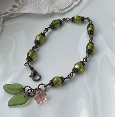 The green bracelet with leaves and a little pink flower. This woodland bracelet is made with vintage green glass beads in a very nice shade of moss green that I decorated with different bead caps.  At the end of the bracelet I added 2 vintage glass leaves and a little pink glass button in the shape of a flower.  The leaves and flower are set along the jump rings into which the clasp can be attached. So the length can be from 17 cm to 18.5 cm (7 to 7 1/4 inches). Length is 17 to 18.5 cm (7 to 7 1 Knitting Moodboard, Woodland Bracelet, Czech Glass Jewelry, Green Bracelet, Vintage Green Glass, Leaf Bracelet, Funky Jewelry, Glass Beaded Bracelets, Fall Jewelry