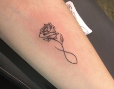 a rose tattoo on the arm with a ribbon around it's neck and an arrow in the middle