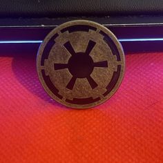 a star wars emblem is shown on the side of a vehicle window sill in front of a red and purple background