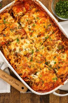 a casserole dish with meat and cheese in it on a wooden table next to some parsley