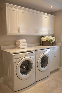 a washer and dryer in a room with white cupboards on the wall