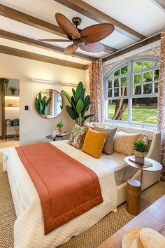 a bedroom with a bed, couch and ceiling fan in front of a large window