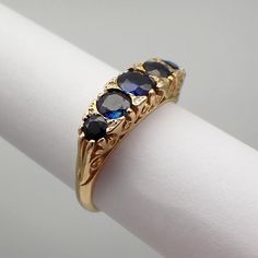 Vintage English 18k (.750) yellow gold ring, featuring ornate setting with 5 Sapphire stones and tiny Diamond accents. Maker's mark - J&P (unknown). This majestic ring is a size 6 1/4, it is 5.36 mm wide, weighing 4.4 grams. EA5543 Victorian Sapphire Jewelry In Gold, Victorian Gold Sapphire Jewelry, Formal Yellow Gold Round Sapphire Ring, Victorian 14k Gold Three-stone Ring, Victorian Three Stone 14k Gold Ring, Antique Yellow Gold Sapphire Ring For Anniversary, Formal Gold Three Stone Rings, Gold Victorian Sapphire Ring, Classic Gold Three-stone Sapphire Ring