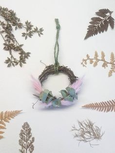 various plants and branches are arranged on a white surface, including an artificial wreath with pink feathers