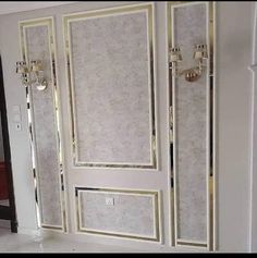 an empty room with white walls and gold trim on the doors, in front of a mirror