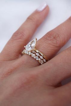 a woman's hand with a diamond ring on top of her finger and an engagement band