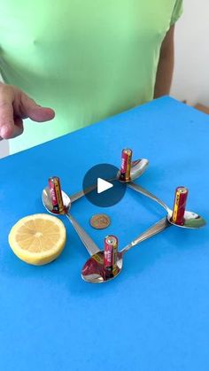 a person pointing at an object made out of soda cans and lemon slices on a blue table