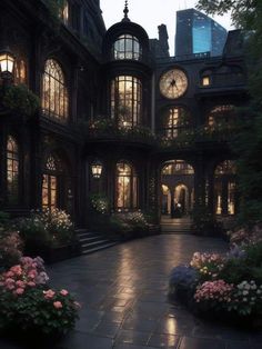 a large building with lots of windows and flowers in the front yard at night time