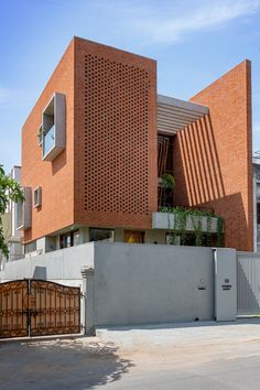 an orange brick building on the corner of a street in front of a fence and gate