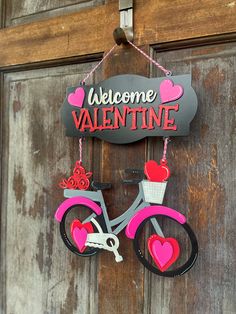 a bicycle hanging on a door with the words welcome valentine written in pink and red