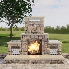 a stone fire pit sitting on top of a brick patio next to a tree and grass covered field